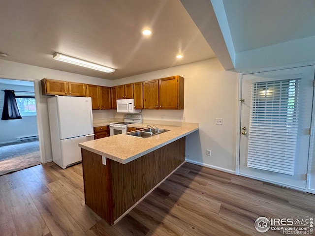 3565 Windmill Dr Unit 3, Fort Collins, CO 80526 - kitchen featuring white appliances, a peninsula, light countertops, a sink, and wood finished floors