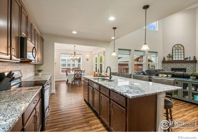 kitchen with a kitchen bar, tasteful backsplash, a sink, dark wood finished floors, and appliances with stainless steel finishes
