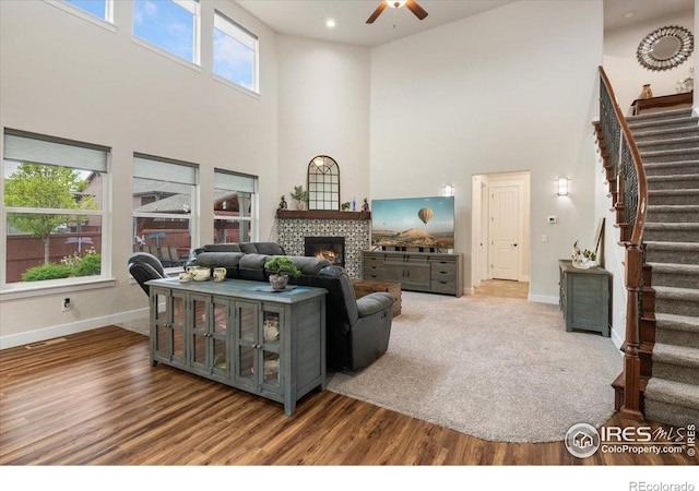 living room with a ceiling fan, baseboards, stairway, and a towering ceiling