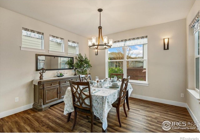 dining space featuring dark wood-style flooring, baseboards, and a notable chandelier