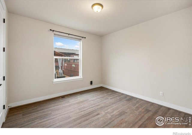 unfurnished room featuring baseboards, wood finished floors, and visible vents