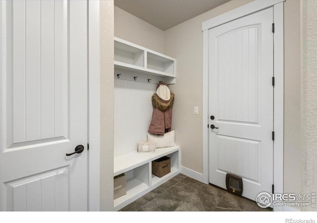 mudroom with dark tile patterned flooring and baseboards