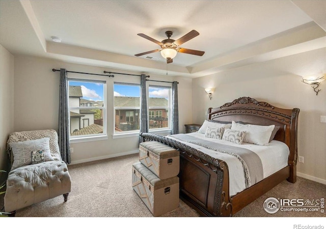 bedroom with visible vents, baseboards, ceiling fan, a tray ceiling, and carpet