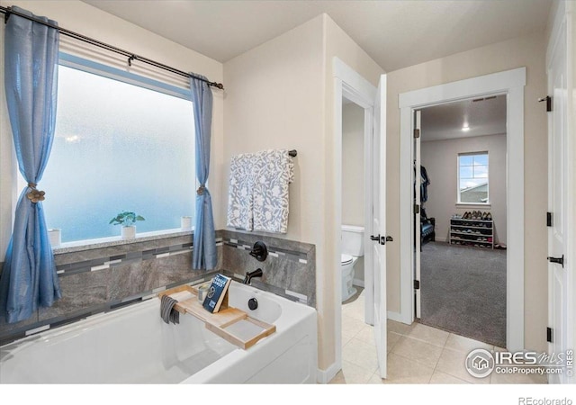 full bathroom with a garden tub, baseboards, tile patterned flooring, and toilet