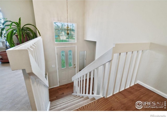 13755 W 65th Dr, Arvada, CO 80004 - stairway featuring a chandelier, wood finished floors, a towering ceiling, and baseboards