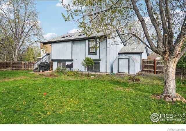 13755 W 65th Dr, Arvada, CO 80004 - back of property featuring a shed, a shingled roof, roof mounted solar panels, and an outdoor structure