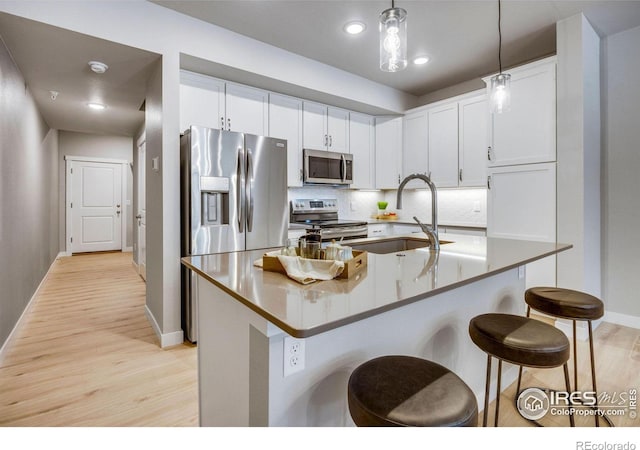 968 Birdwhistle Ln Unit 6, Fort Collins, CO 80524 - kitchen with stainless steel appliances, light wood-style flooring, a sink, a kitchen bar, and baseboards