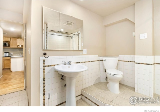 511 Spindrift Ct, Fort Collins, CO 80525 - bathroom featuring toilet, tile walls, a wainscoted wall, tile patterned floors, and a sink