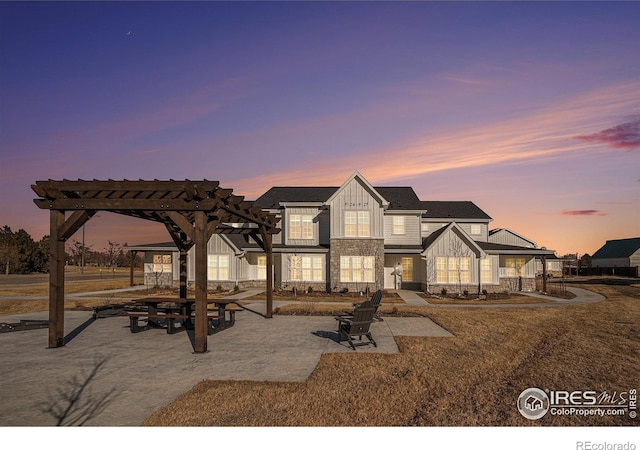back of property with board and batten siding, stone siding, and a pergola