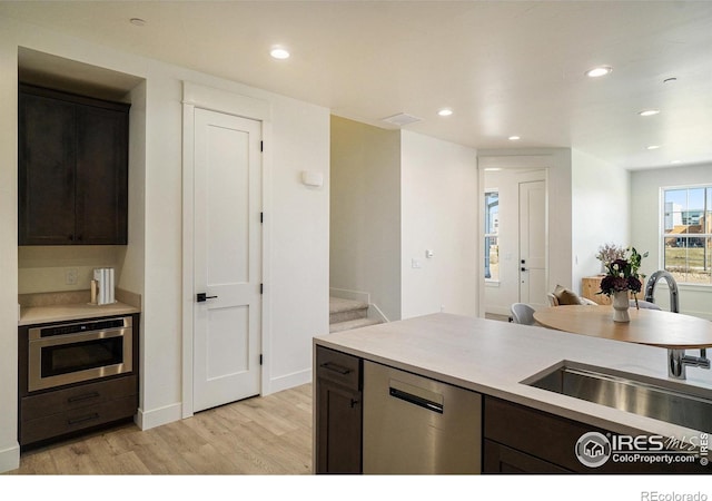 kitchen featuring appliances with stainless steel finishes, light wood-style flooring, a sink, light countertops, and recessed lighting