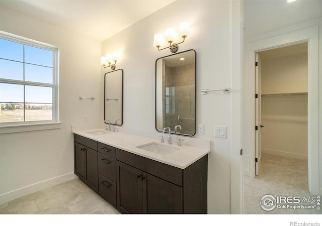 bathroom with baseboards, a walk in closet, double vanity, and a shower