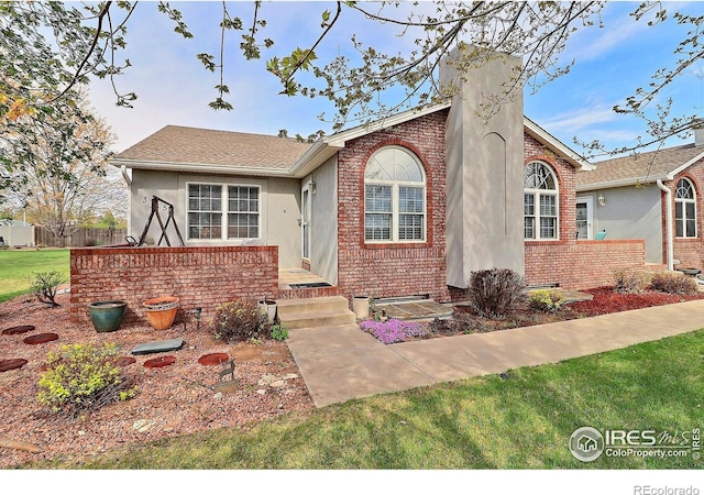 355 47th Ave Unit A, Greeley, CO 80634 - view of front of property featuring fence, stucco siding, a chimney, and brick siding