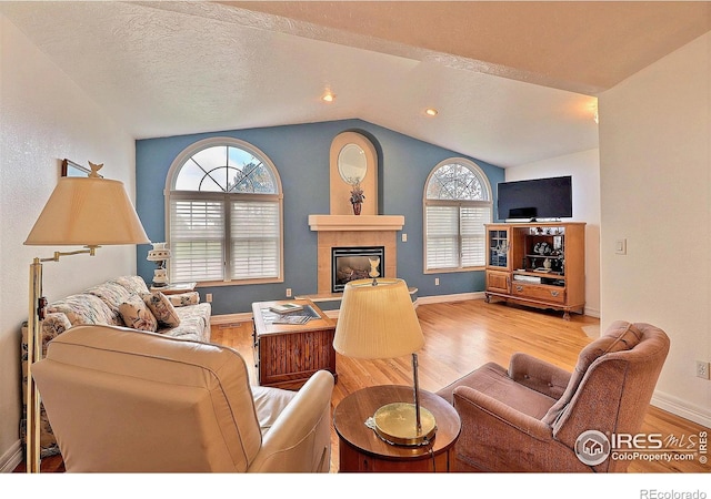355 47th Ave Unit A, Greeley, CO 80634 - living room featuring baseboards, a tile fireplace, wood finished floors, and lofted ceiling