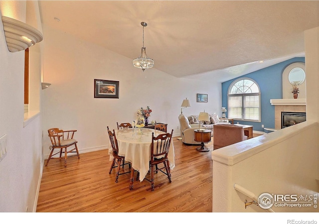 355 47th Ave Unit A, Greeley, CO 80634 - dining space with baseboards, vaulted ceiling, light wood-style flooring, and a tile fireplace