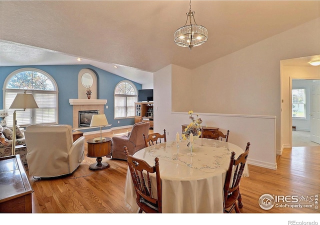 355 47th Ave Unit A, Greeley, CO 80634 - dining room featuring a wealth of natural light, wood finished floors, vaulted ceiling, and a fireplace