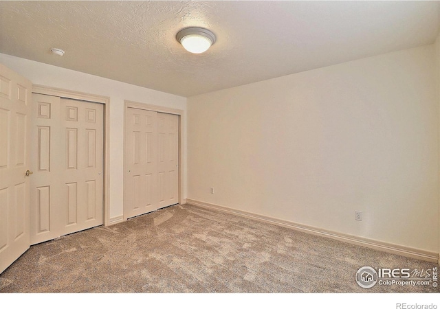 355 47th Ave Unit A, Greeley, CO 80634 - unfurnished bedroom with multiple closets, baseboards, carpet flooring, and a textured ceiling