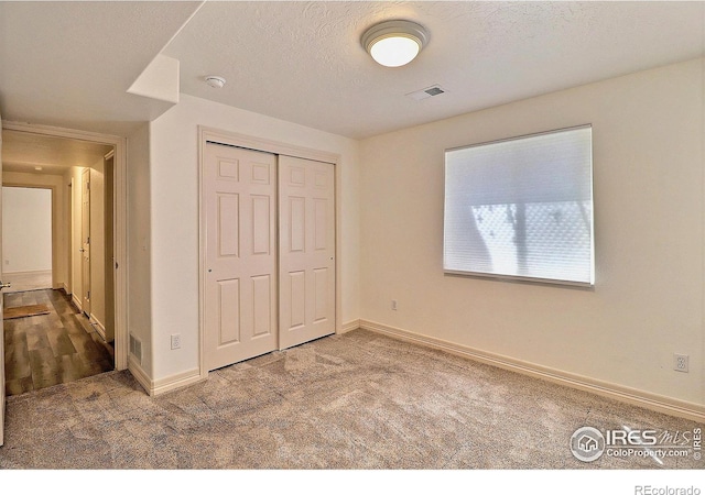 355 47th Ave Unit A, Greeley, CO 80634 - unfurnished bedroom with a textured ceiling, visible vents, baseboards, a closet, and carpet