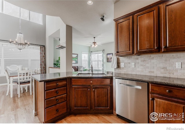 kitchen with a peninsula, light wood-type flooring, a sink, ceiling fan with notable chandelier, and dishwasher