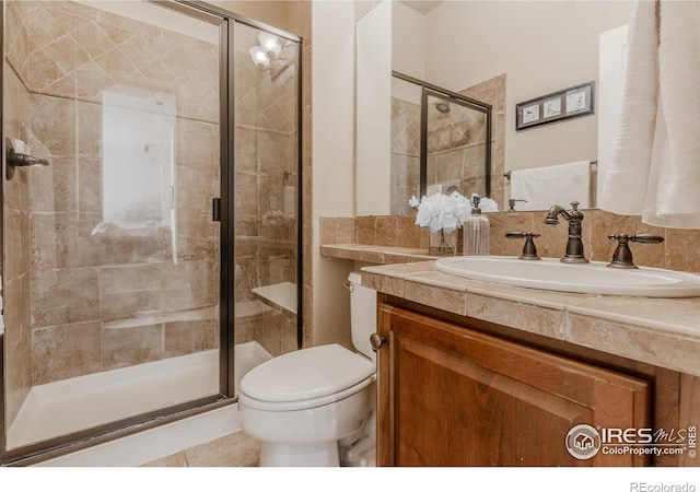 bathroom featuring toilet, tile patterned floors, a shower stall, and vanity