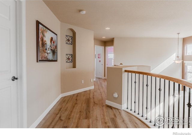 corridor with recessed lighting, baseboards, an upstairs landing, and light wood-type flooring