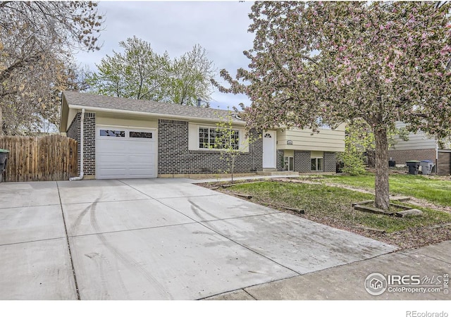 1352 S Terry St, Longmont, CO 80501 - view of front of house featuring driveway, brick siding, fence, a front lawn, and an attached garage