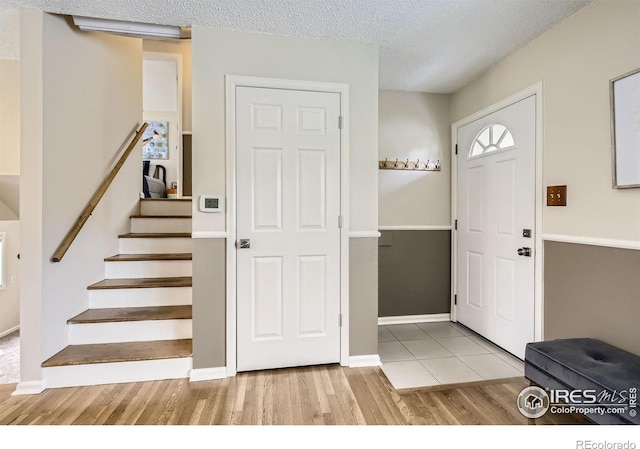 1352 S Terry St, Longmont, CO 80501 - entryway featuring stairway, a textured ceiling, baseboards, and wood finished floors