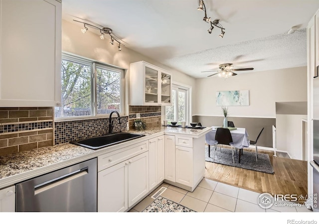 1352 S Terry St, Longmont, CO 80501 - kitchen with stainless steel dishwasher, a sink, track lighting, glass insert cabinets, and white cabinetry