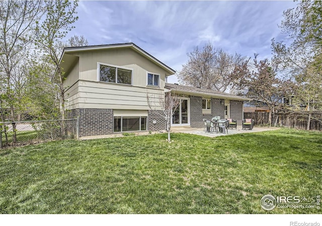 1352 S Terry St, Longmont, CO 80501 - rear view of property featuring brick siding, a fenced backyard, a lawn, and a patio area