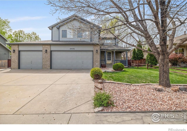 2476 Forsythia Dr, Loveland, CO 80537 - traditional-style house featuring driveway, a front yard, a garage, brick siding, and fence