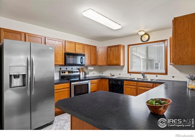 2476 Forsythia Dr, Loveland, CO 80537 - kitchen featuring brown cabinetry, dark countertops, a sink, black appliances, and a peninsula