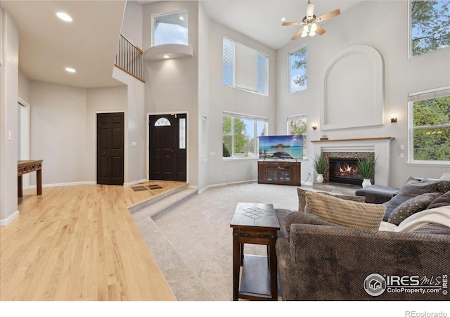 8355 Louden Circle Ft, Collins, CO 80528 - living area featuring baseboards, a glass covered fireplace, a towering ceiling, and a wealth of natural light