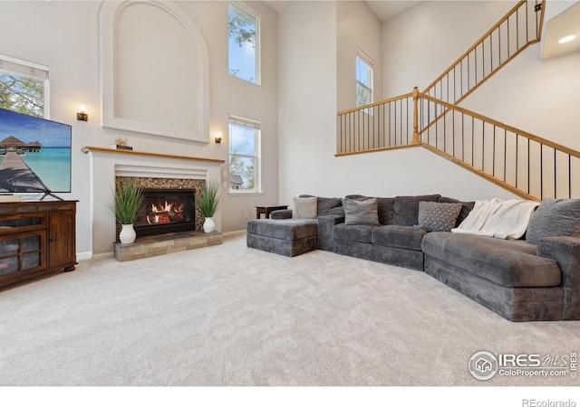 8355 Louden Circle Ft, Collins, CO 80528 - living room with a high ceiling, carpet floors, a tiled fireplace, stairs, and baseboards