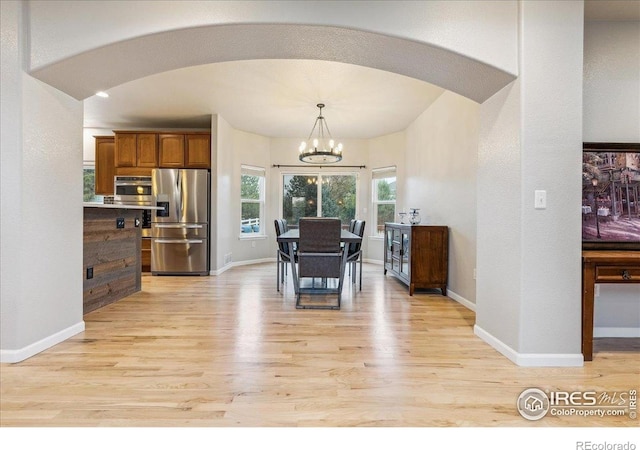 8355 Louden Circle Ft, Collins, CO 80528 - dining space with light wood-style floors, arched walkways, baseboards, and a notable chandelier