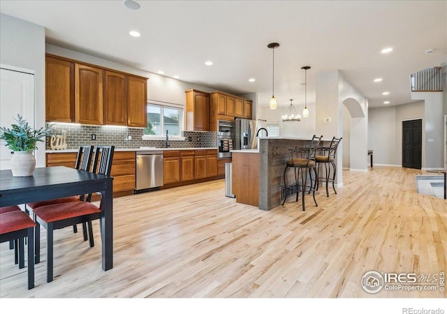 8355 Louden Circle Ft, Collins, CO 80528 - kitchen featuring brown cabinets, backsplash, stainless steel appliances, and light wood finished floors