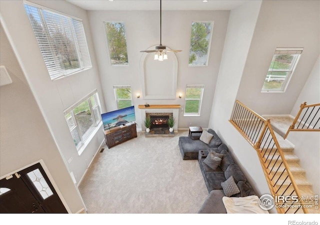 8355 Louden Circle Ft, Collins, CO 80528 - living area featuring carpet floors, a towering ceiling, a lit fireplace, stairway, and a ceiling fan