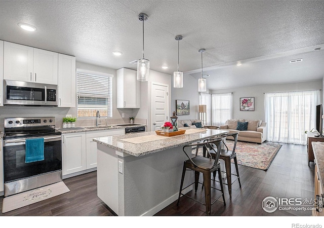 403 11th Ave, Wiggins, CO 80654 - kitchen with visible vents, open floor plan, a center island, a sink, and stainless steel appliances