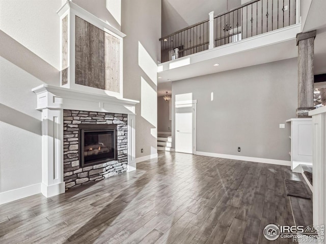 unfurnished living room with baseboards, a high ceiling, wood finished floors, and a fireplace