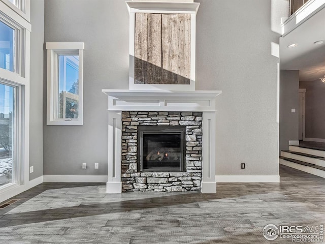 unfurnished living room with a high ceiling, a fireplace, and wood finished floors