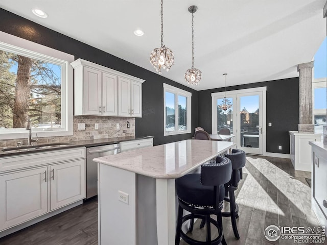 kitchen with a sink, dishwasher, a chandelier, tasteful backsplash, and dark wood-style floors