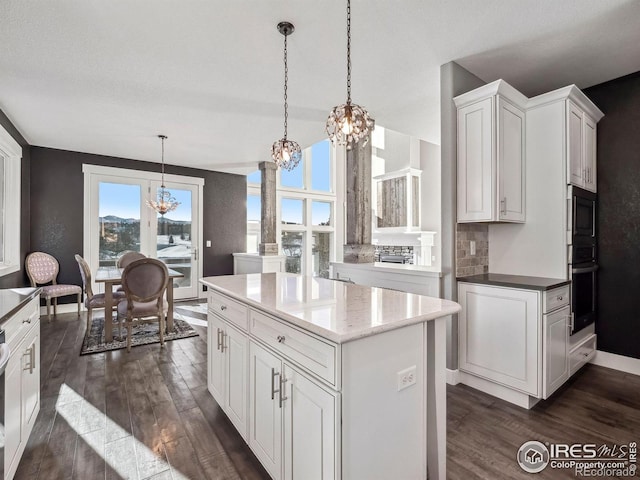 kitchen with white cabinetry, a chandelier, dark wood-style floors, and ornate columns