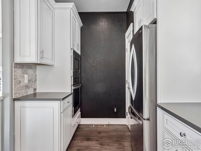 kitchen with visible vents, dark countertops, appliances with stainless steel finishes, dark wood finished floors, and white cabinetry