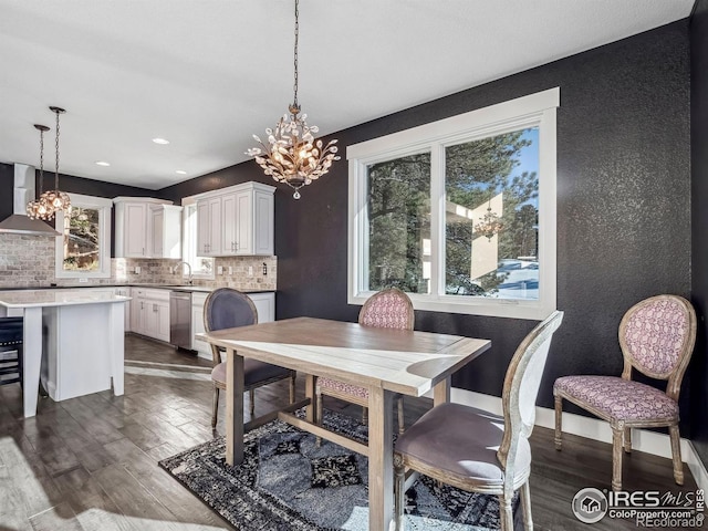 dining space with dark wood-style flooring, a textured wall, and a notable chandelier