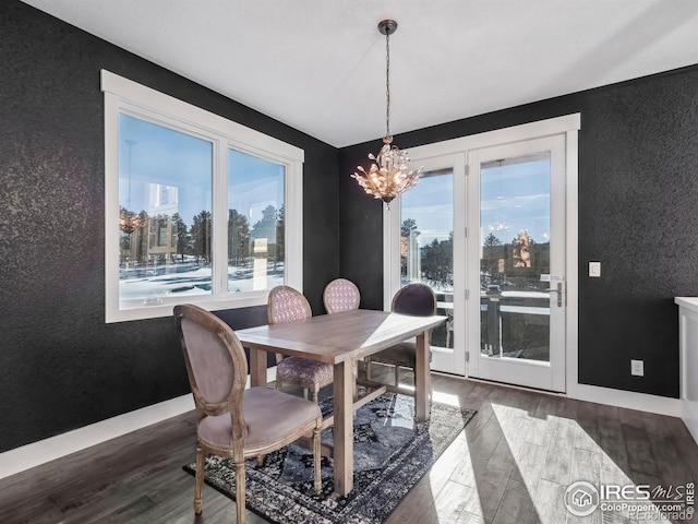 dining area with baseboards, a textured wall, wood finished floors, and a chandelier