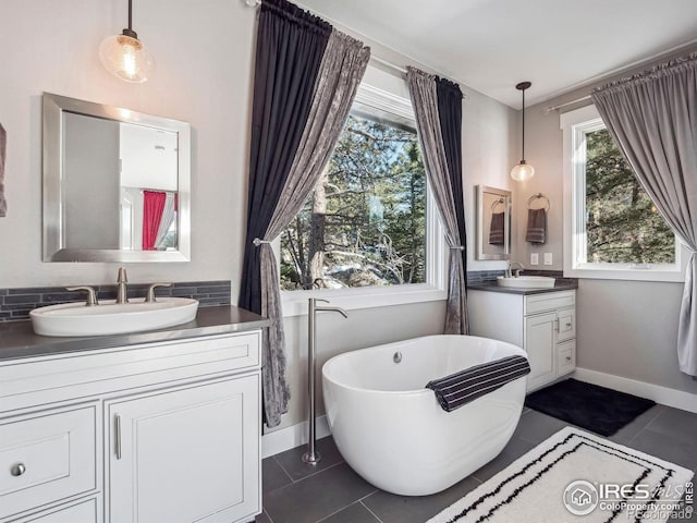 full bathroom featuring baseboards, two vanities, and a sink