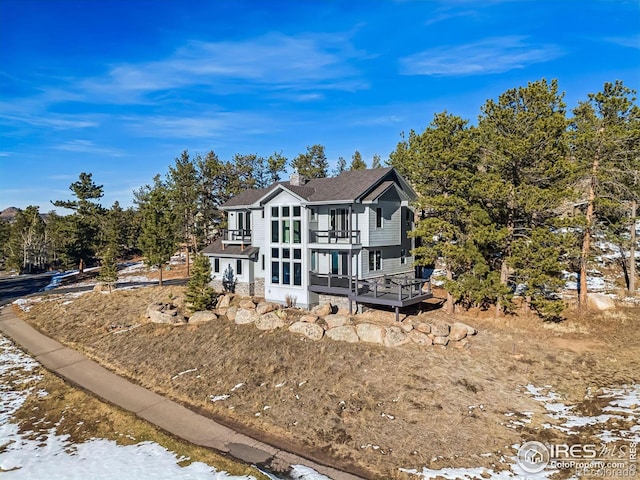 view of front of home with a deck, a shingled roof, and a balcony