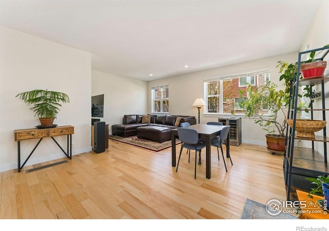 living area with beverage cooler, recessed lighting, baseboards, and light wood-style flooring