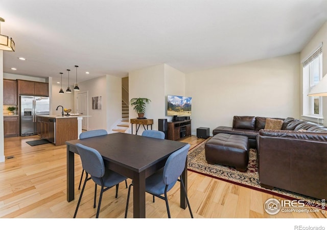 dining room featuring recessed lighting, light wood-style flooring, and stairway
