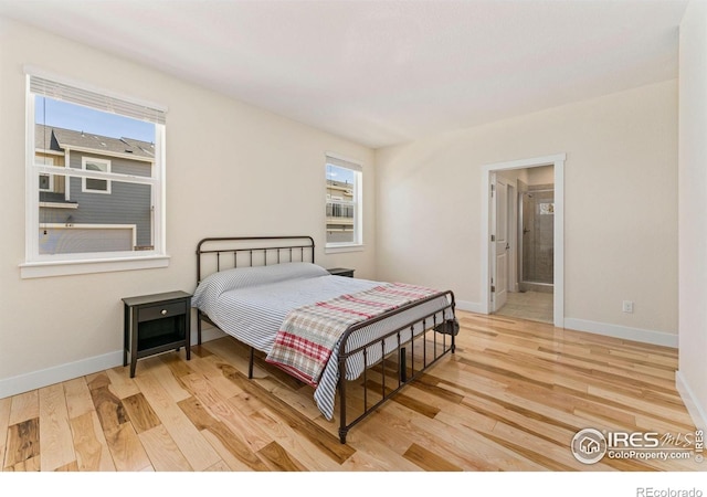 bedroom featuring baseboards, wood finished floors, and ensuite bath