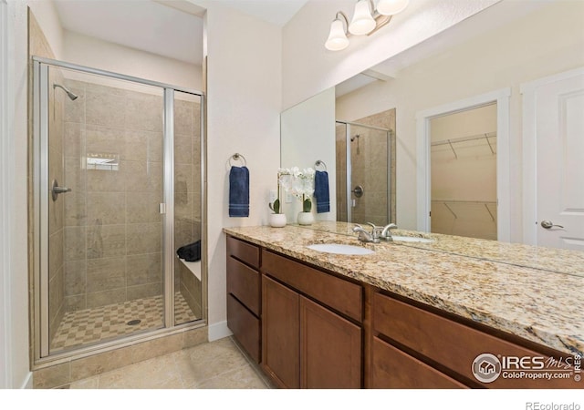 bathroom featuring vanity, tile patterned floors, a shower stall, and a walk in closet