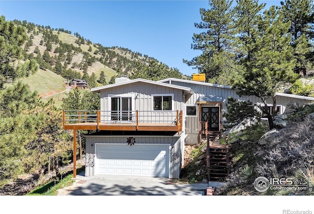 2345 Point Of Pines Dr, Boulder, CO 80302 - view of front of house featuring an attached garage, stairway, a mountain view, a chimney, and concrete driveway